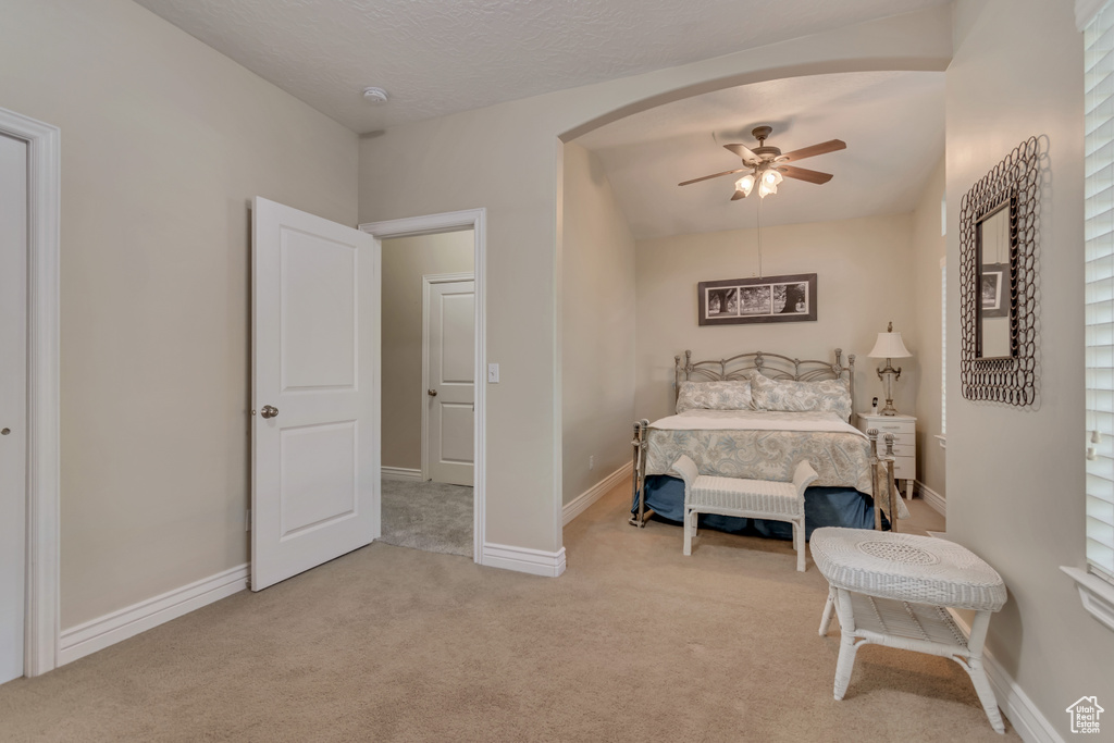 Bedroom with light carpet, baseboards, ceiling fan, and arched walkways