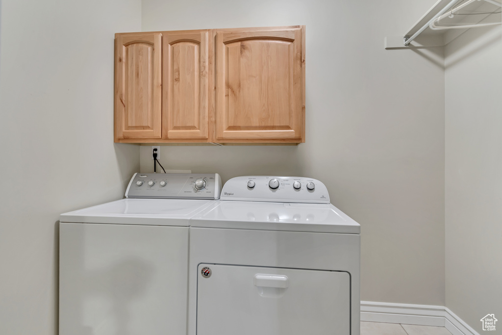 Washroom with washing machine and clothes dryer, cabinet space, and tile patterned flooring