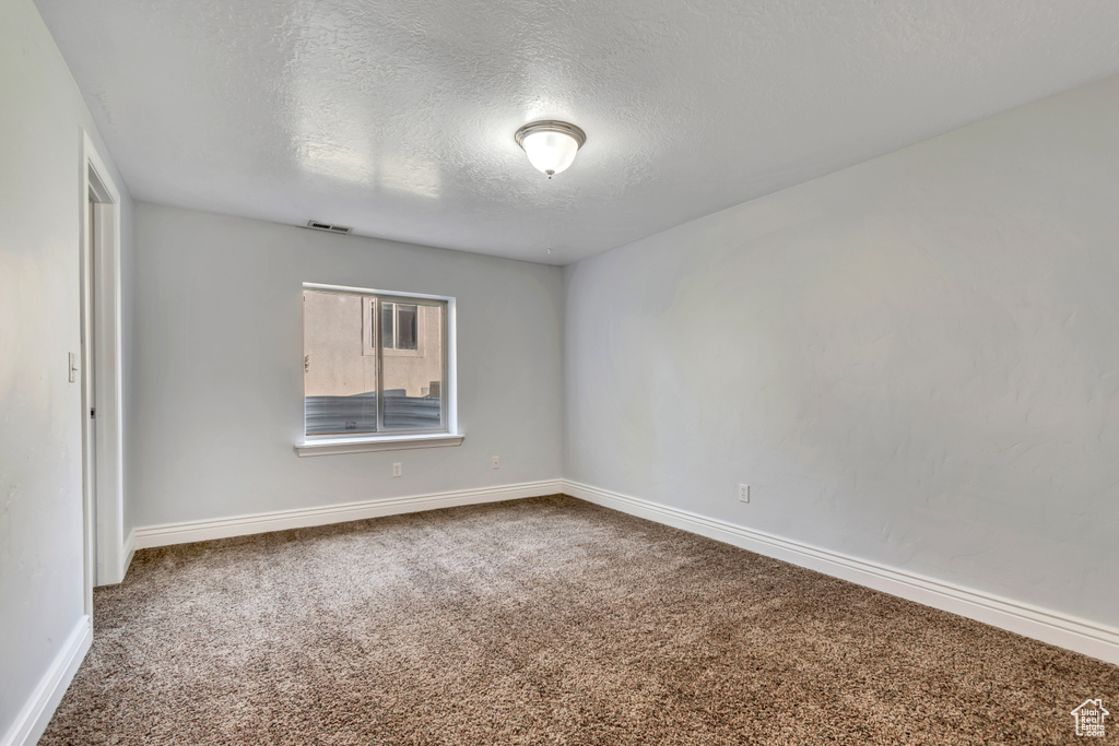 Spare room with carpet flooring, a textured ceiling, and baseboards