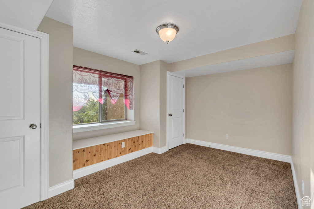 Spare room featuring dark carpet and baseboards