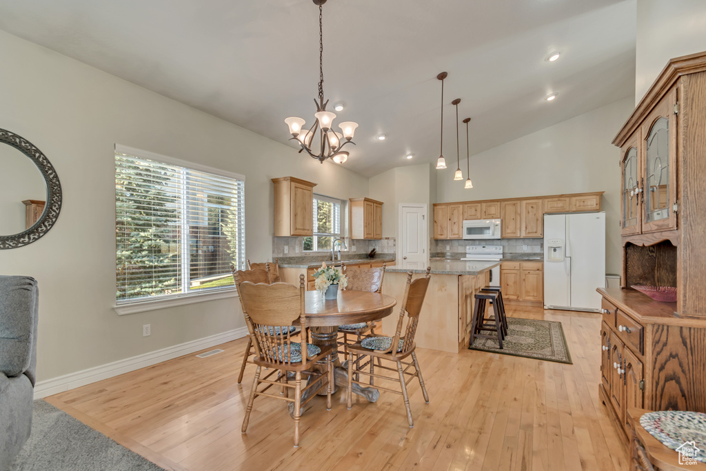 Dining space featuring light wood-style flooring, baseboards, a chandelier, lofted ceiling, and recessed lighting