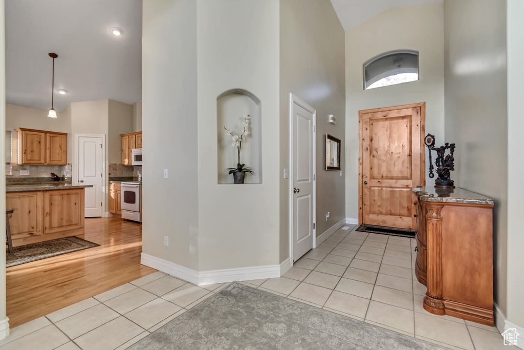 Foyer entrance with high vaulted ceiling, light tile patterned flooring, and baseboards