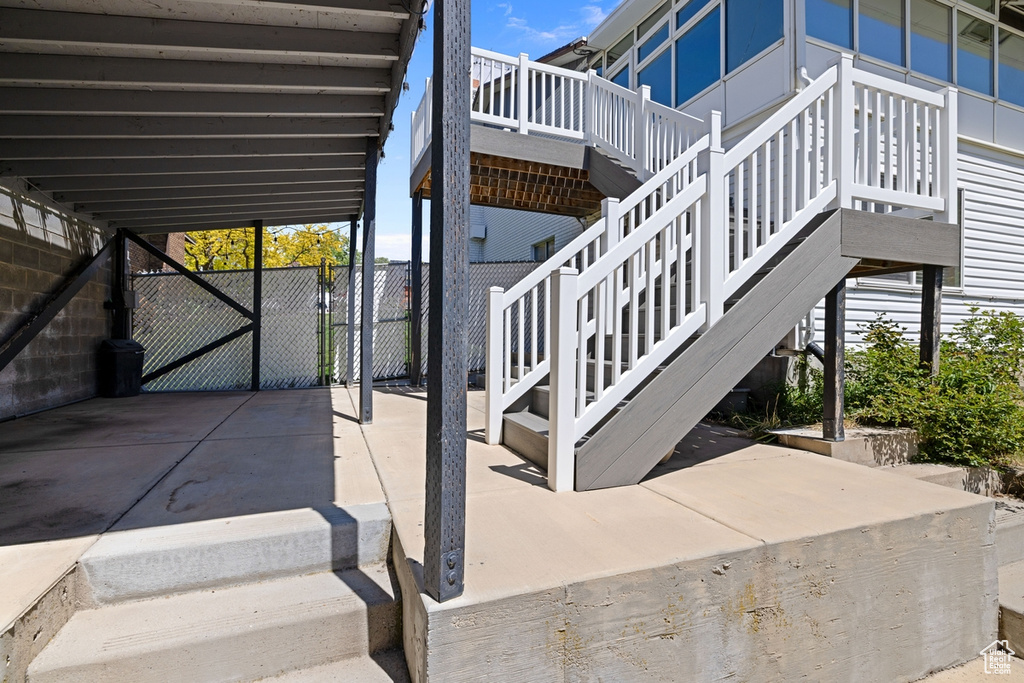 View of patio featuring fence, stairs, and a deck