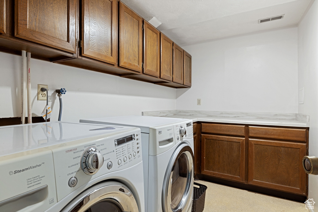 Laundry room featuring separate washer and dryer and cabinet space