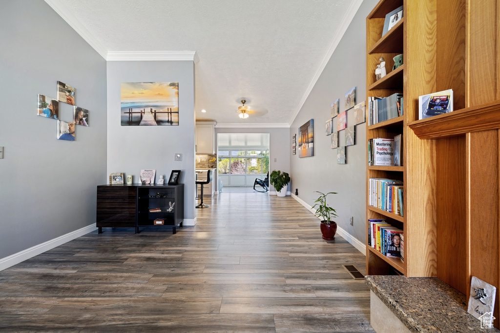 Corridor with ornamental molding, dark wood-style flooring, and baseboards