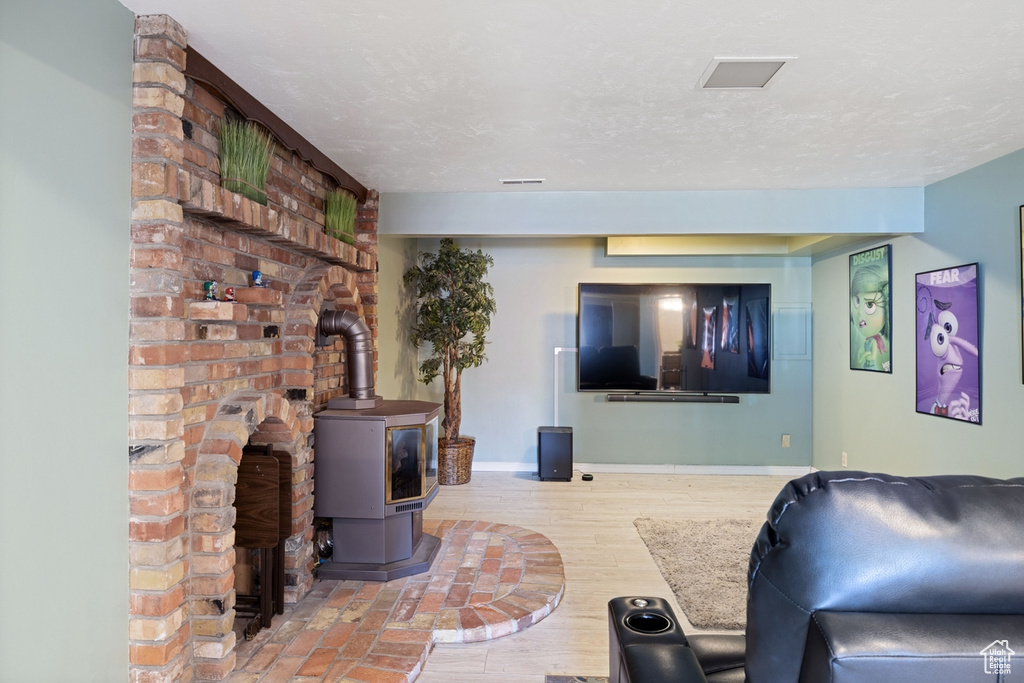 Living room with baseboards, a wood stove, and wood finished floors