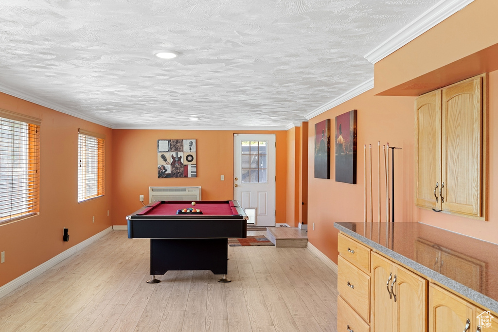Recreation room with billiards, light wood-style flooring, baseboards, crown molding, and an AC wall unit