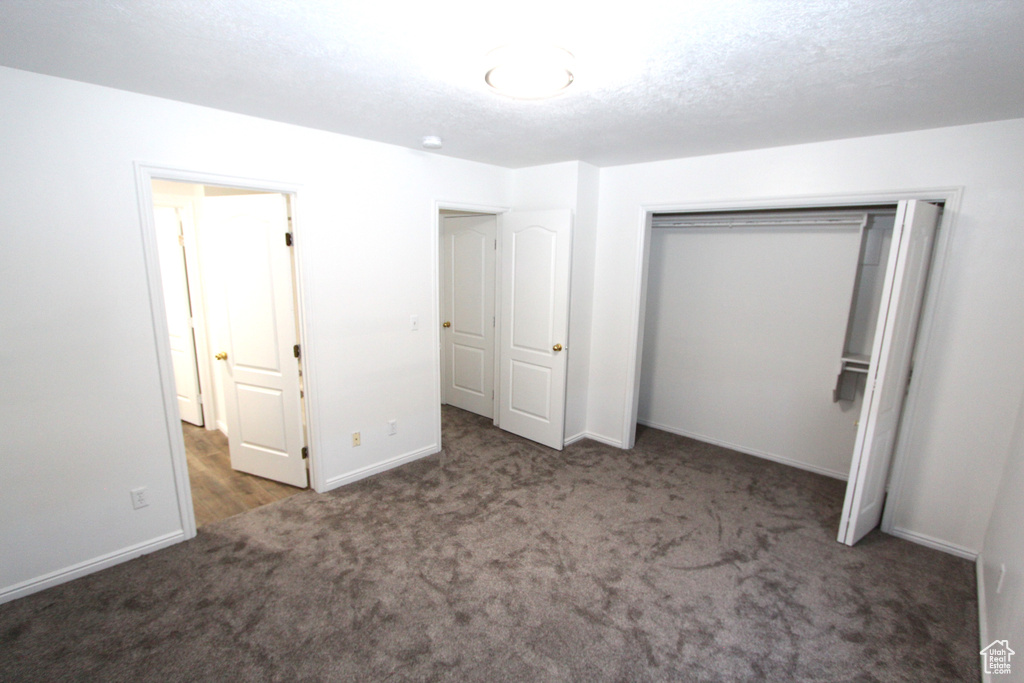 Unfurnished bedroom featuring carpet floors, baseboards, and a closet