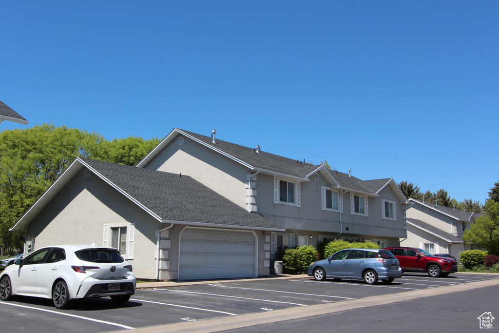 View of front of home with stucco siding and uncovered parking