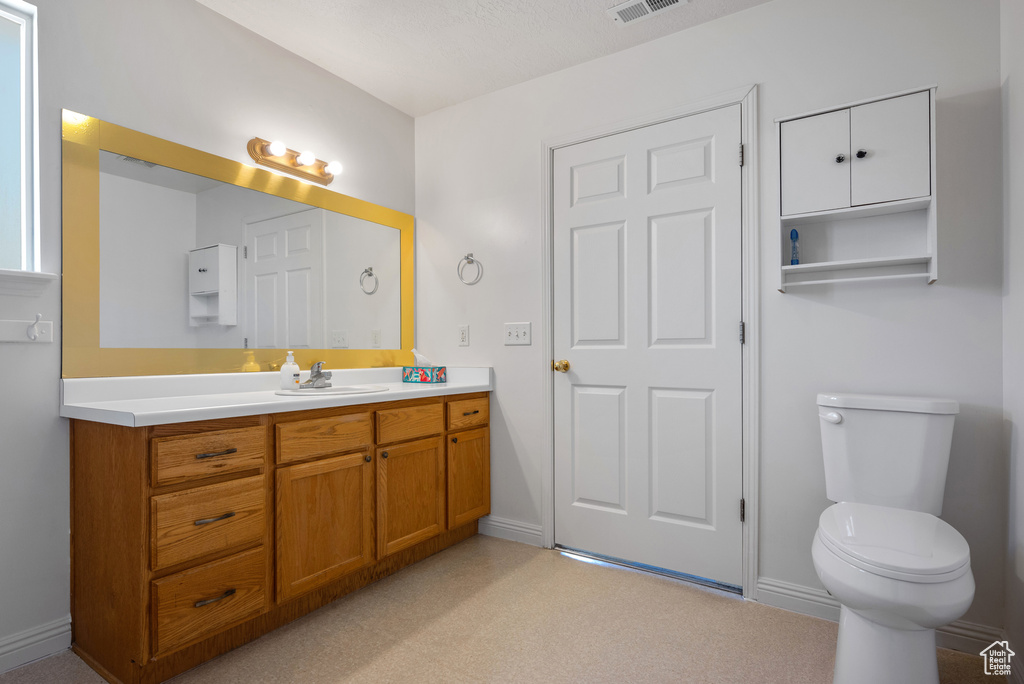 Bathroom featuring vanity, toilet, and baseboards