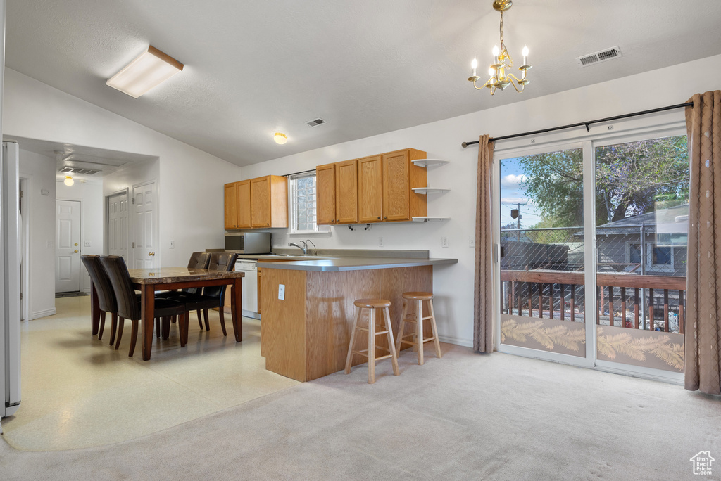 Kitchen featuring vaulted ceiling, a chandelier, a breakfast bar, open shelves, and a peninsula