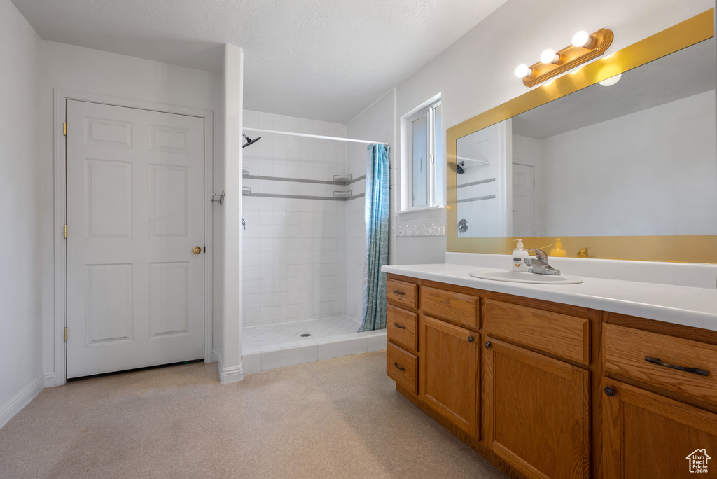 Full bath featuring a tile shower and vanity