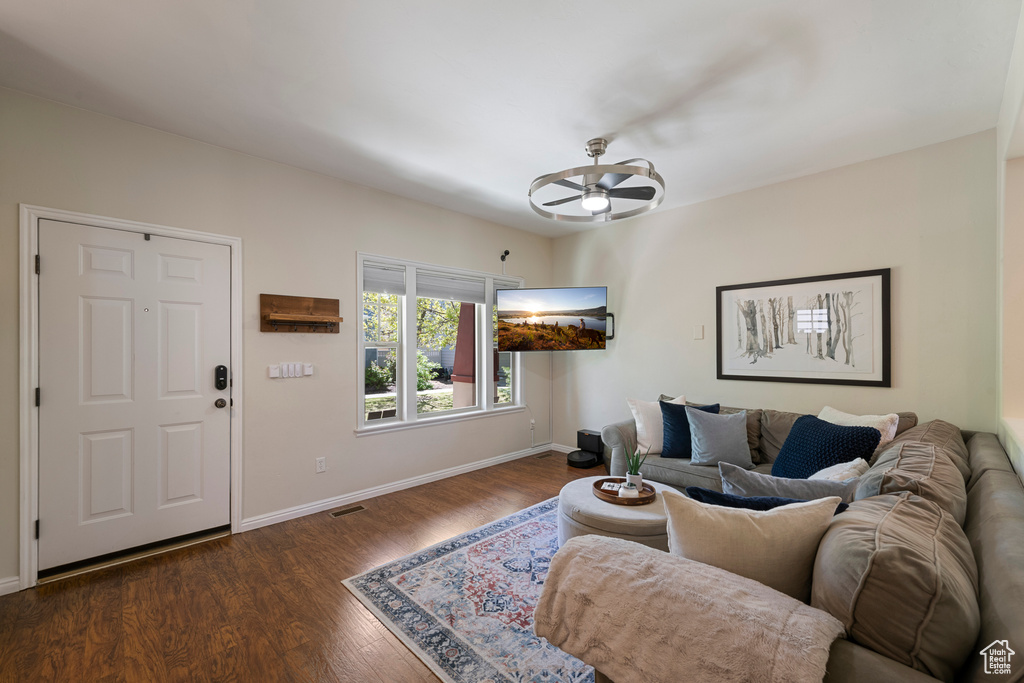 Living room featuring dark wood-type flooring, baseboards, a ceiling fan, and visible vents