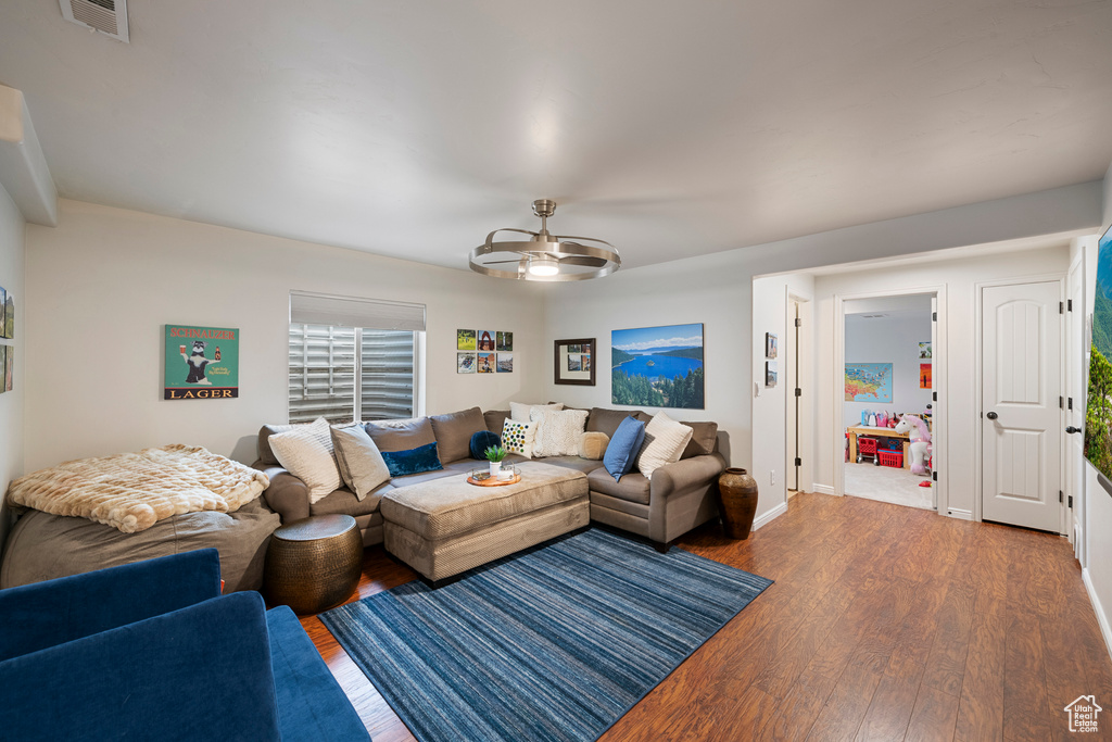 Living room featuring dark wood finished floors, visible vents, baseboards, and a ceiling fan