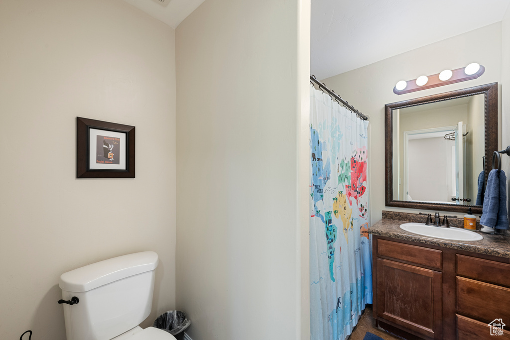 Full bathroom with toilet, curtained shower, and vanity