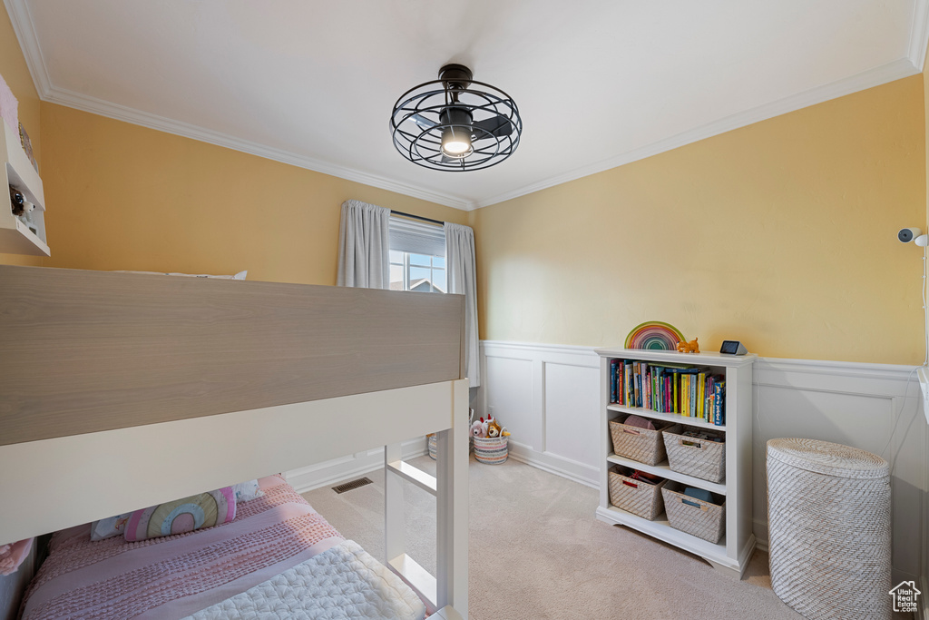 Carpeted bedroom featuring wainscoting and ornamental molding