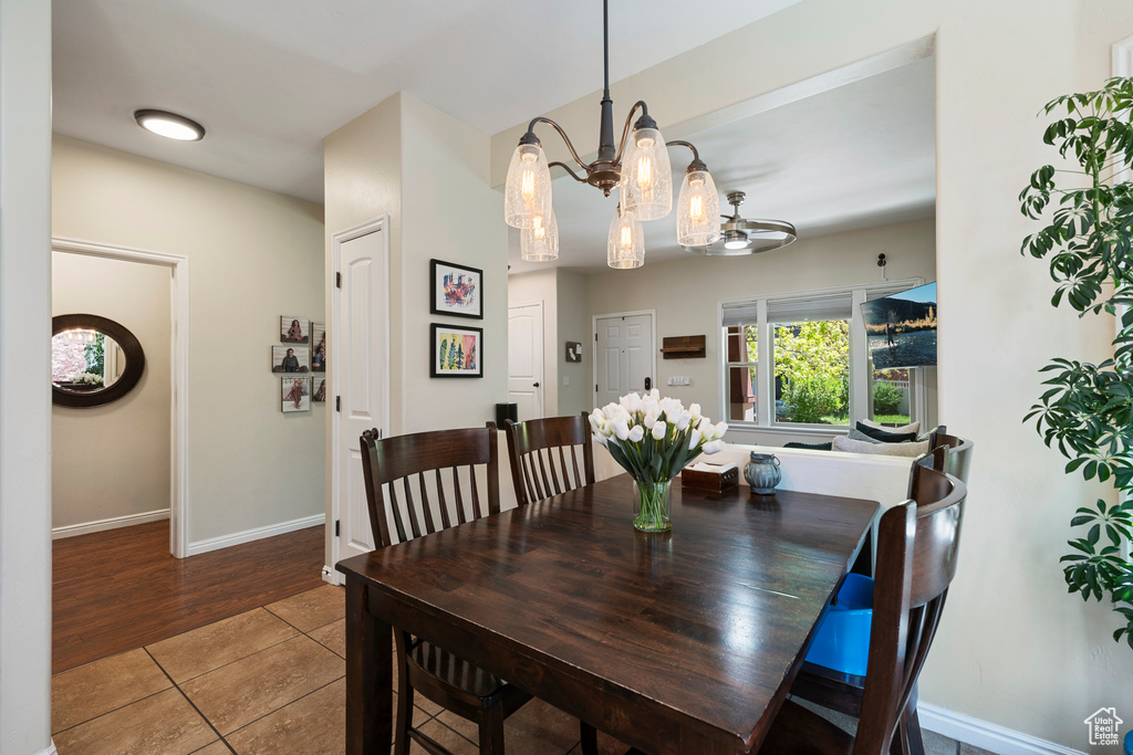 Tiled dining space featuring a chandelier and baseboards