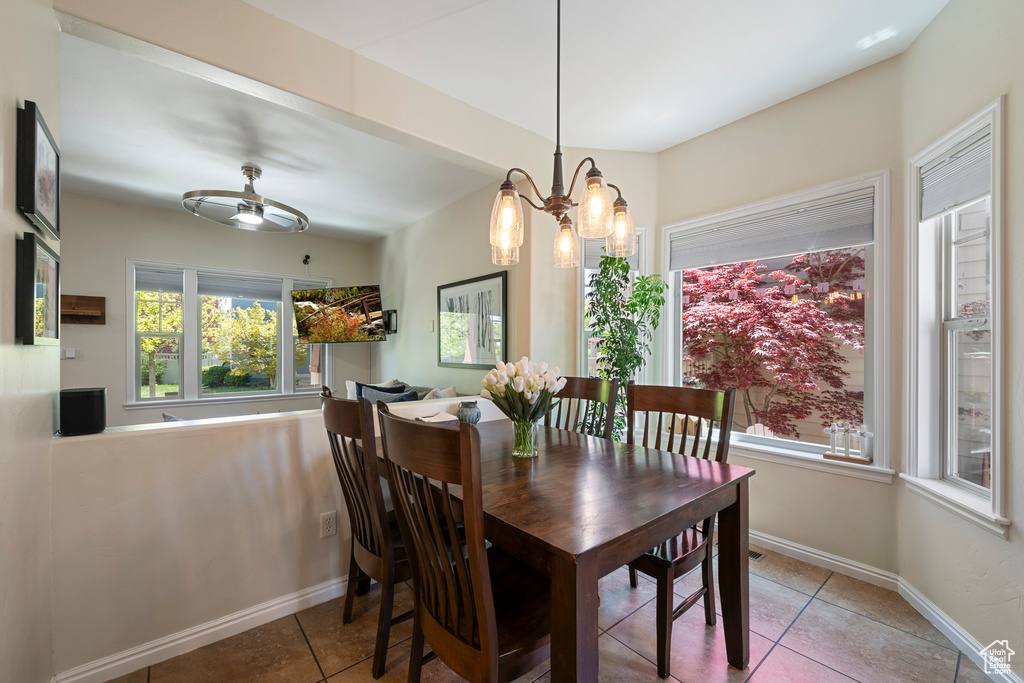 Dining area with tile patterned flooring, baseboards, and a notable chandelier