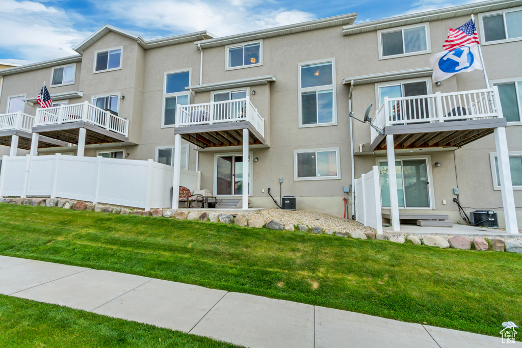 Back of property featuring stucco siding, a lawn, and central air condition unit