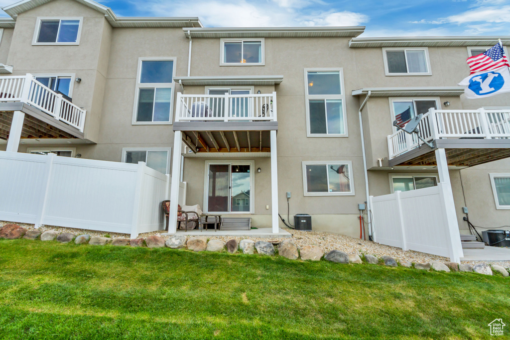 Rear view of house featuring stucco siding, central AC unit, and a balcony