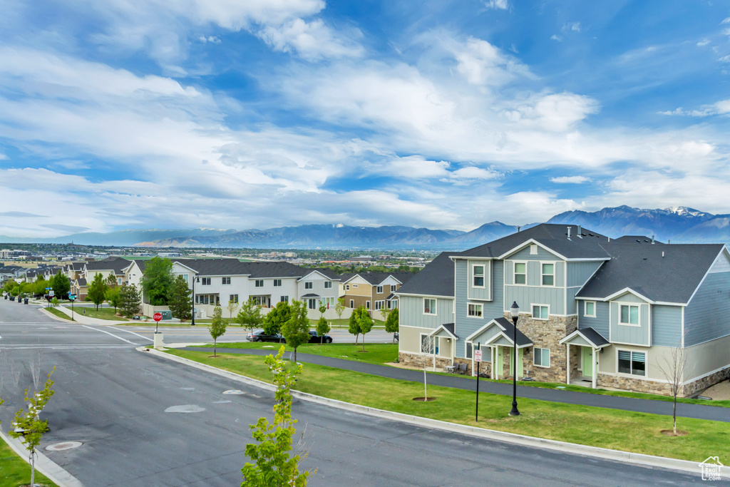 View of asphalt road with traffic signs, a residential view, a mountain view, and curbs