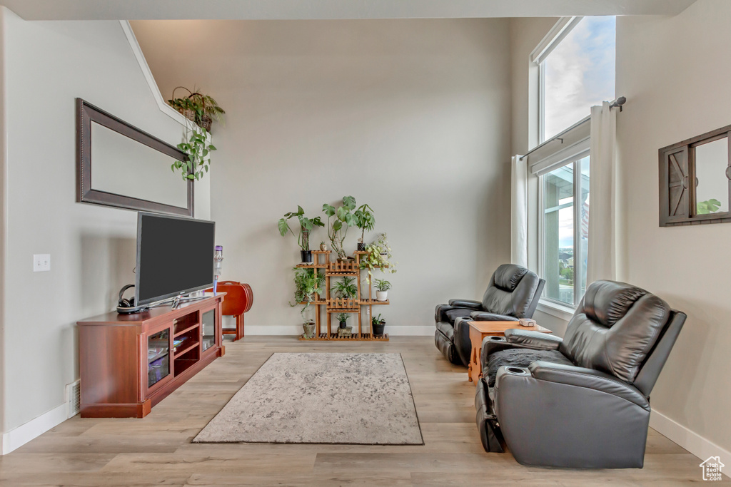 Living room featuring light wood-style flooring, baseboards, and a high ceiling