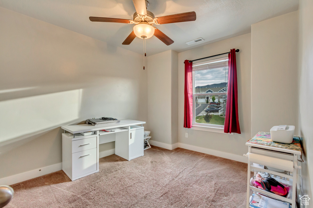 Unfurnished office featuring light colored carpet, baseboards, and a ceiling fan