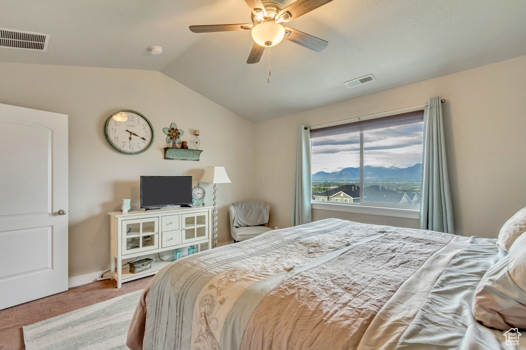 Carpeted bedroom featuring vaulted ceiling and a ceiling fan