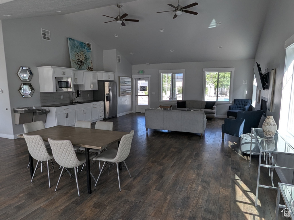 Dining area featuring high vaulted ceiling, dark wood-type flooring, baseboards, and a ceiling fan