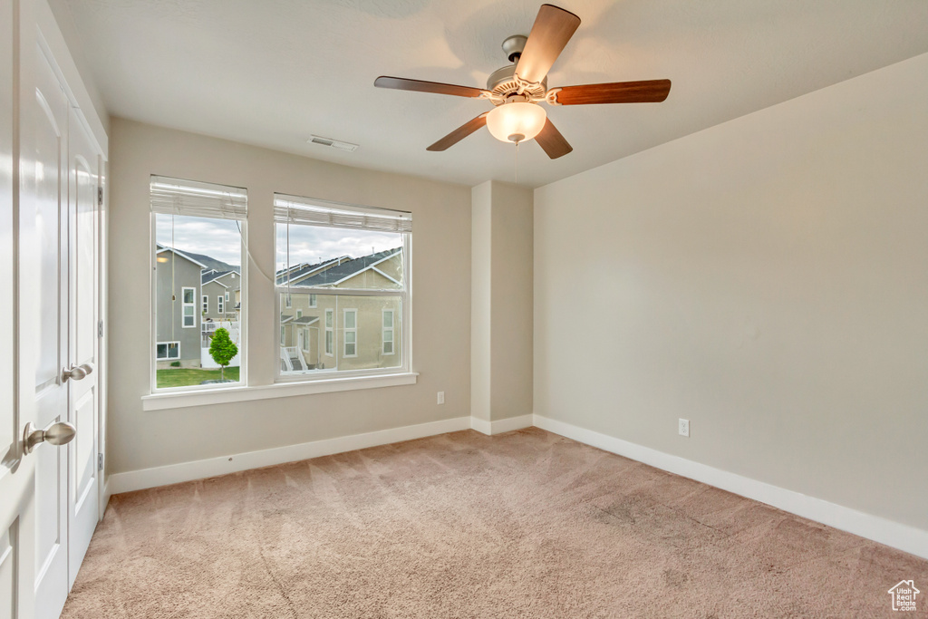 Carpeted spare room featuring baseboards and a ceiling fan