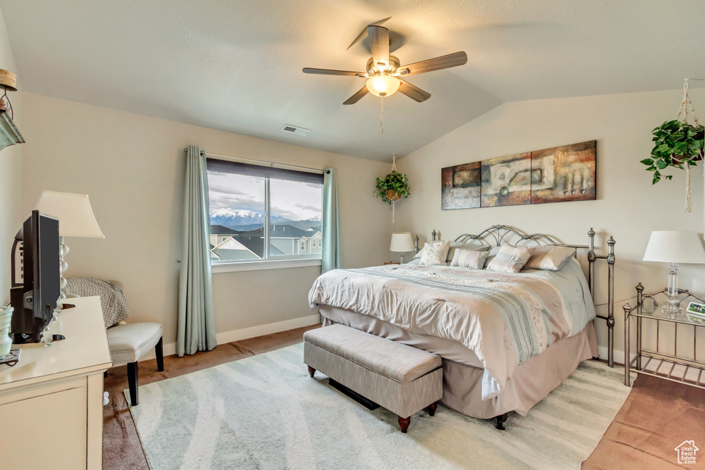 Bedroom featuring light colored carpet, vaulted ceiling, baseboards, and a ceiling fan