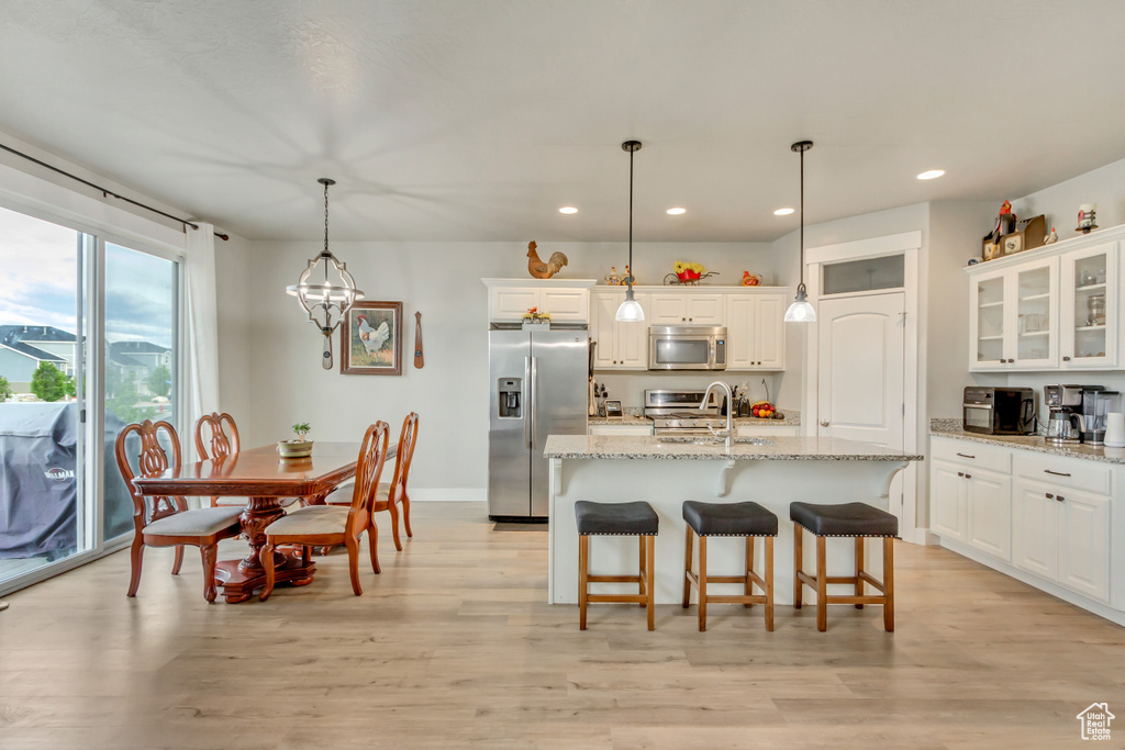 Kitchen featuring appliances with stainless steel finishes, recessed lighting, white cabinetry, a breakfast bar area, and light stone countertops