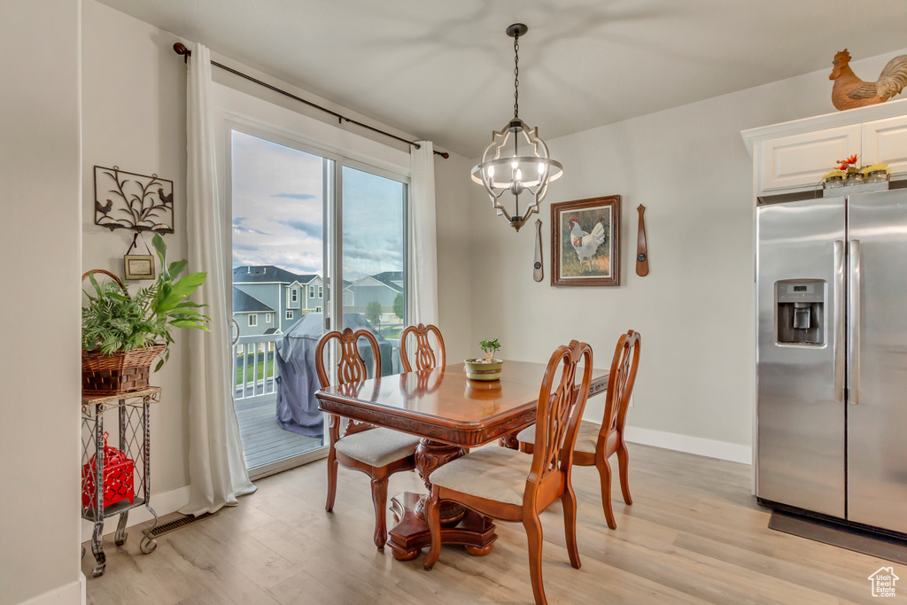 Dining area featuring light wood-type flooring, baseboards, and a chandelier