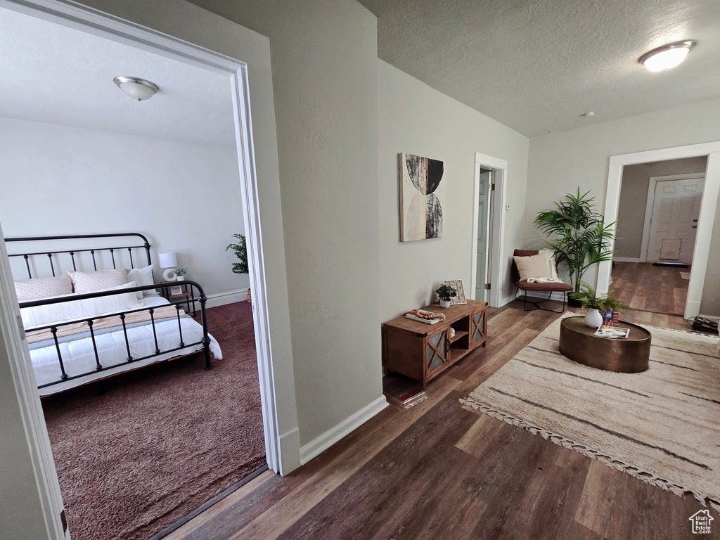 Hallway with wood finished floors, baseboards, and a textured ceiling