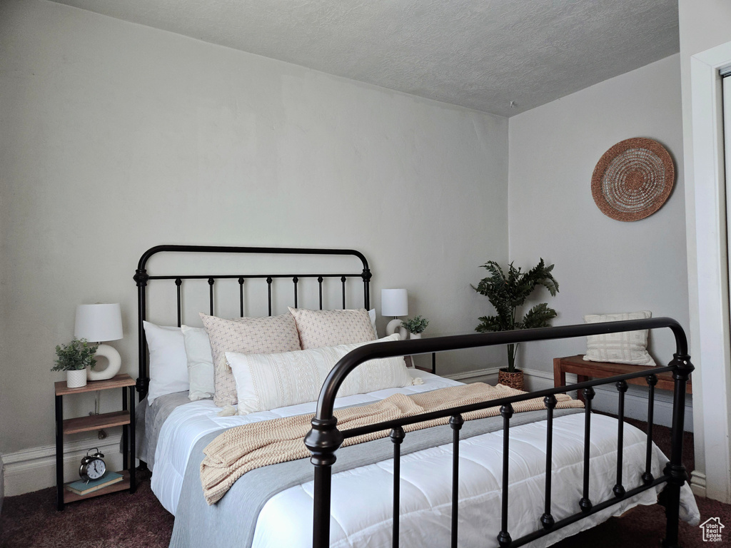 Bedroom featuring carpet floors, a textured ceiling, and baseboards