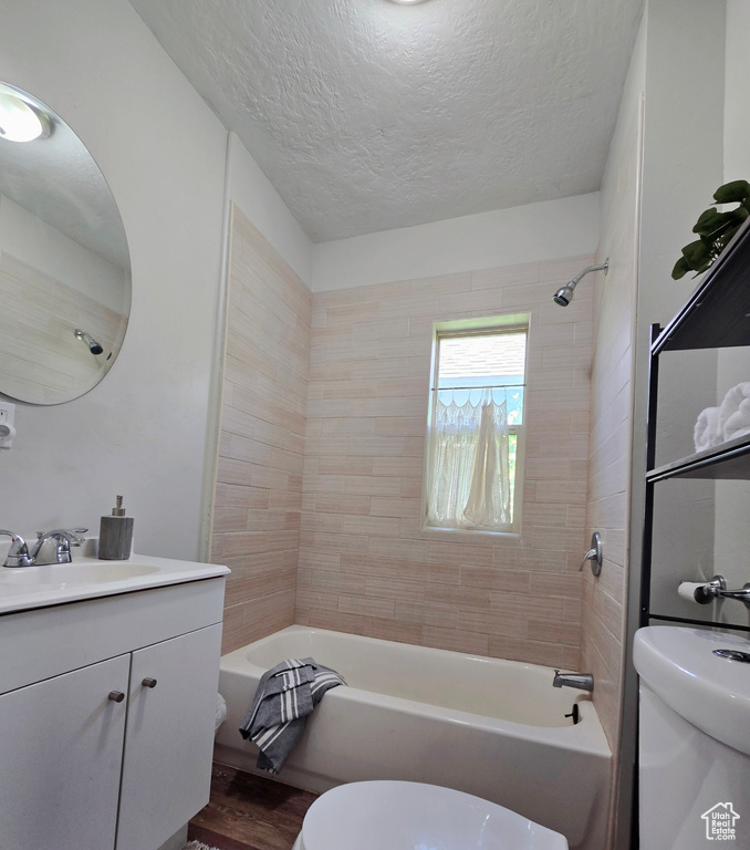 Full bath with toilet, bathing tub / shower combination, vanity, a textured ceiling, and wood finished floors