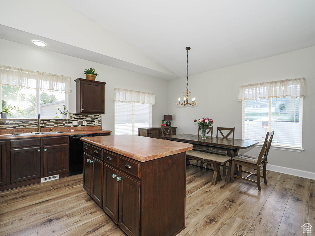Kitchen with a sink, light wood-type flooring, plenty of natural light, lofted ceiling, and dishwasher