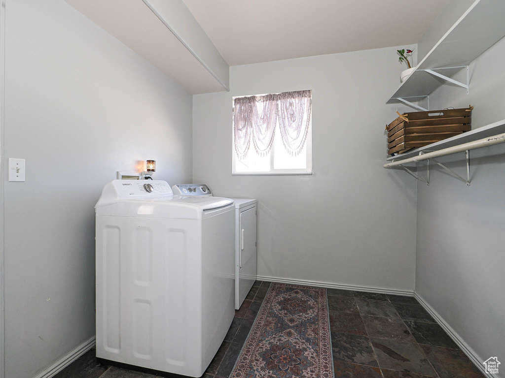 Washroom featuring washer and dryer, baseboards, and dark stone finish flooring