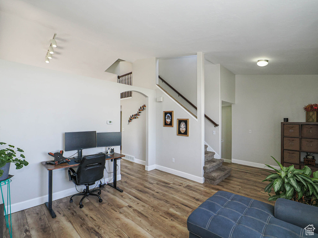 Home office with wood finished floors, baseboards, and rail lighting