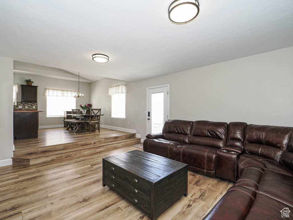 Living room featuring a chandelier, wood finished floors, baseboards, and lofted ceiling