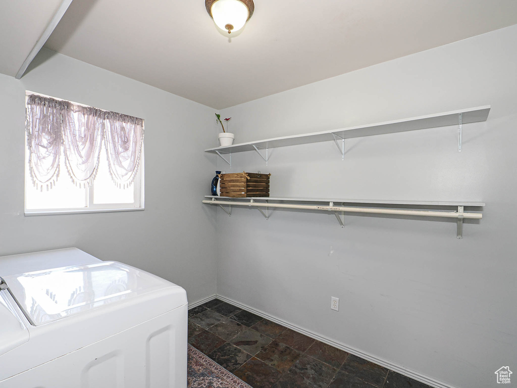 Washroom featuring washer and clothes dryer, dark stone finish floors, and baseboards