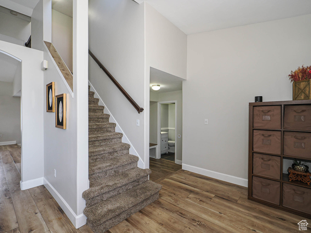 Stairway with wood finished floors, baseboards, and arched walkways