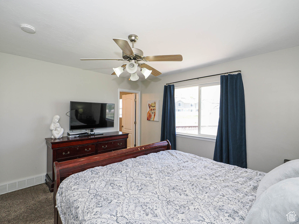 Carpeted bedroom with a ceiling fan and baseboards