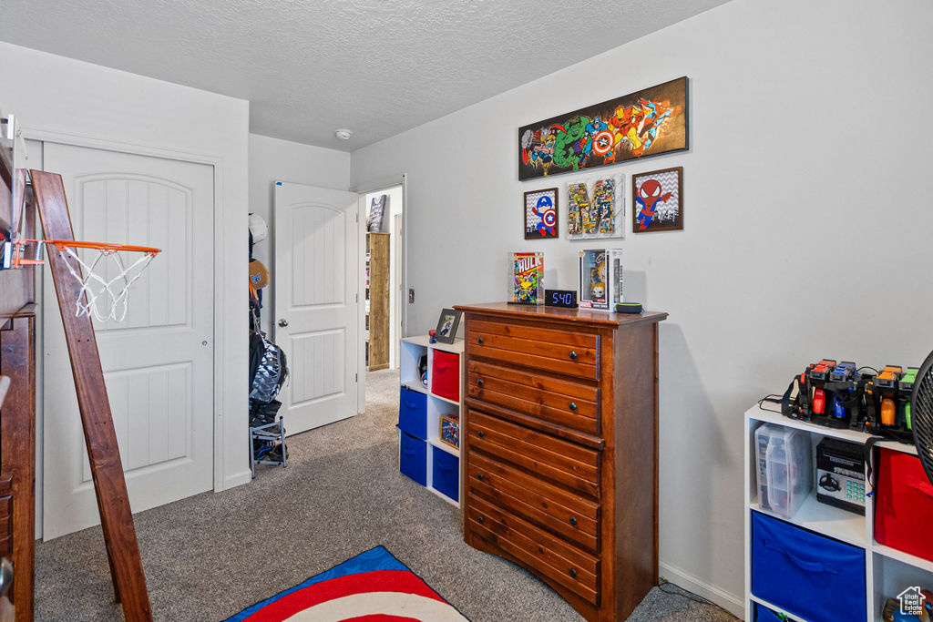 Carpeted bedroom featuring a textured ceiling and baseboards