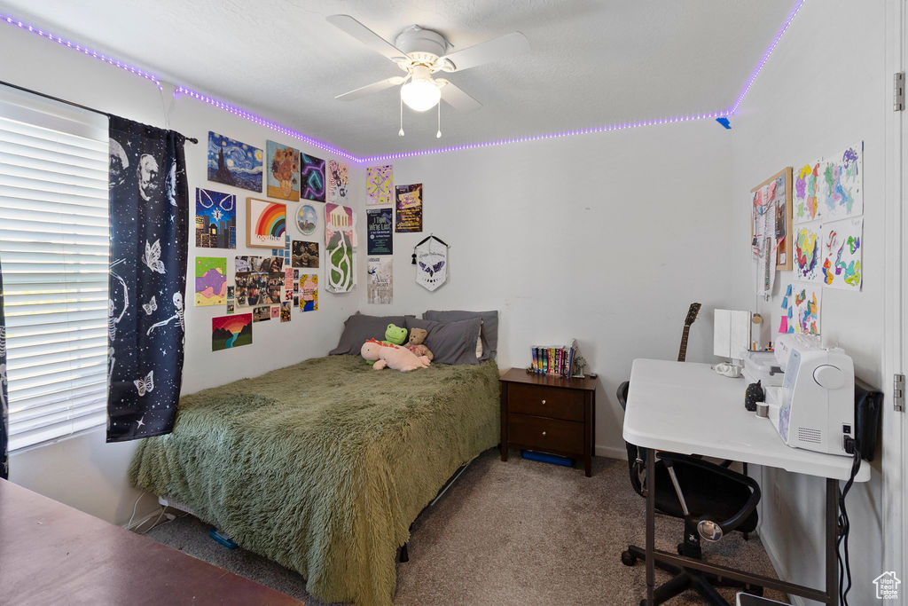 Carpeted bedroom featuring ceiling fan and an office area