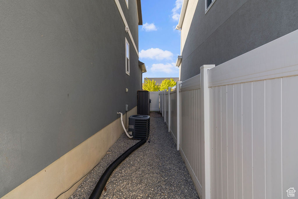View of side of home featuring fence, stucco siding, and cooling unit