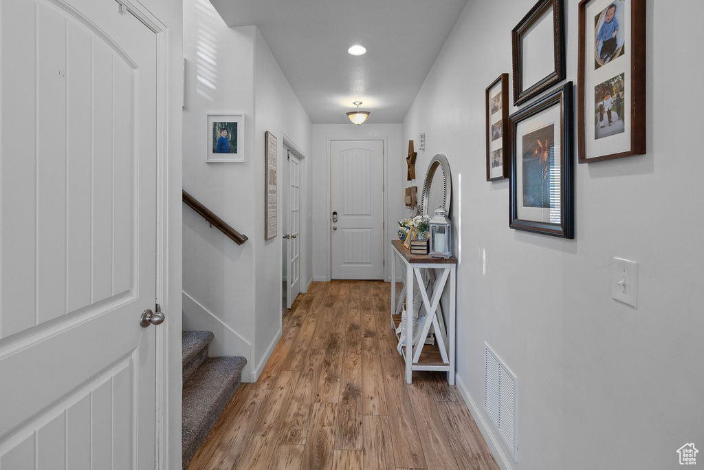 Hallway with wood finished floors, baseboards, stairs, and recessed lighting