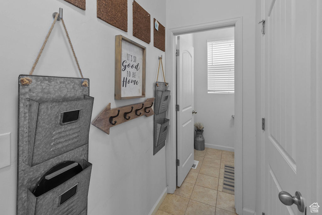 Clothes washing area featuring light tile patterned floors and baseboards