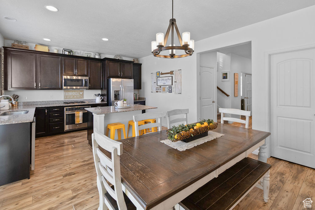 Dining space with a chandelier, light wood finished floors, recessed lighting, and stairs