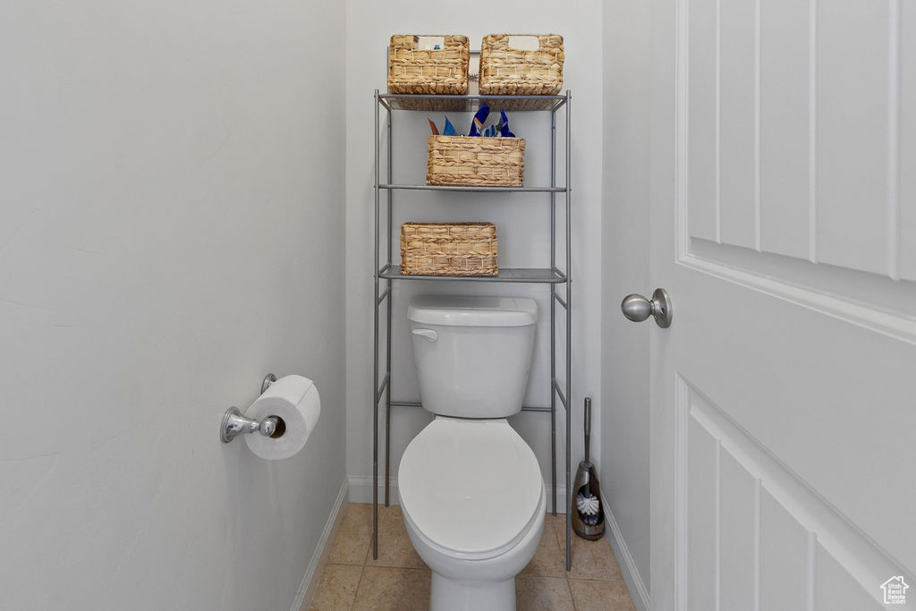 Bathroom featuring toilet, baseboards, and tile patterned floors